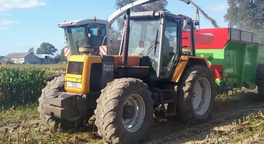 Żółty ciągnik Renault 120.54 z przyczepą podczas żniw kukurydzy. Pytanie o jaki olej do silnika MWM Renault jest tu na miejscu.