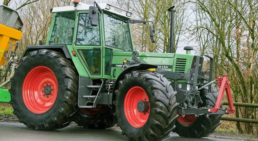 Zielony traktor Fendt 615 LSA z czerwonymi felgami, gotowy do pracy. Poznaj jego dane techniczne!