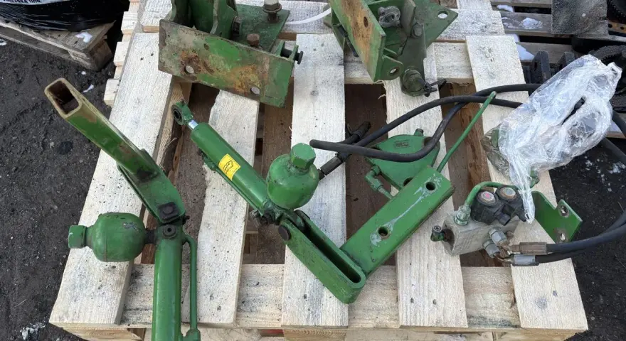 Części do amortyzacji kabiny John Deere: siłownik, wsporniki i elementy hydrauliczne.