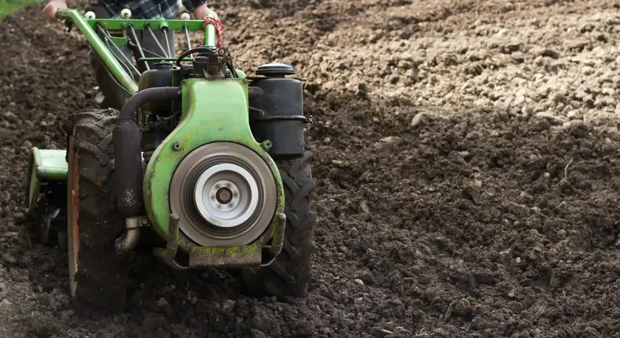 Rolnik używa jednoosiowego ciągnika z pługiem do orki. Różne rodzaje pługów pomagają przygotować ziemię pod uprawę.