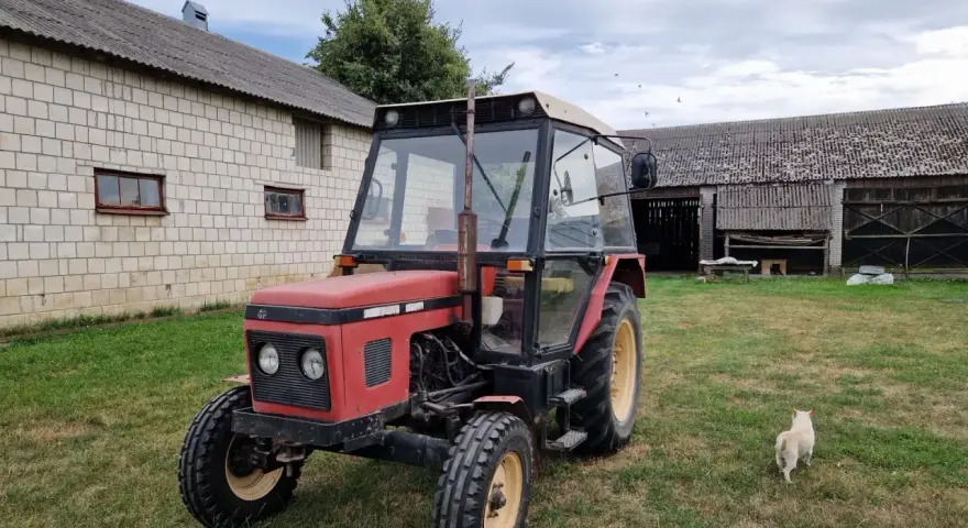 Czerwony Zetor 5011 na trawie, obok budynków gospodarczych. Zastanawiasz się nad jego spalaniem?