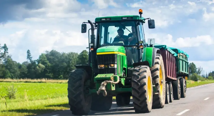 Zielony traktor z przyczepą jedzie po drodze. Zastanawiasz się, ile pali traktor?
