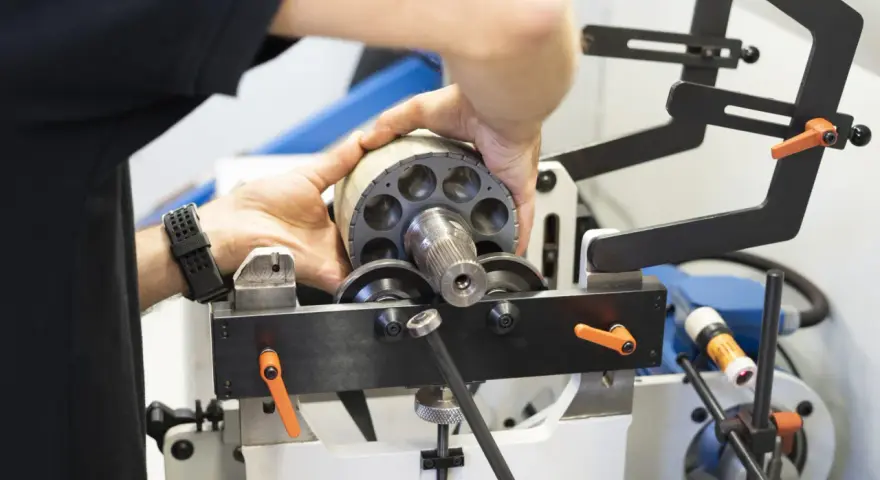 Ręce montują element wirnika pompy hydraulicznej, który jest częścią układu elektrycznego.