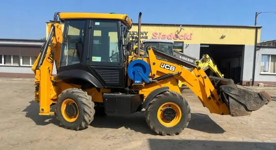Żółta koparko-ładowarka JCB 2CX z ładowarką z przodu i koparką z tyłu, gotowa do pracy. Dane techniczne dostępne dla zainteresowanych.