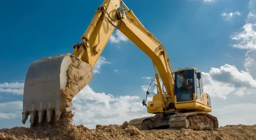 Żółta koparka pracuje na budowie. Zastanawiasz się, ile zarabia operator koparki w Niemczech?