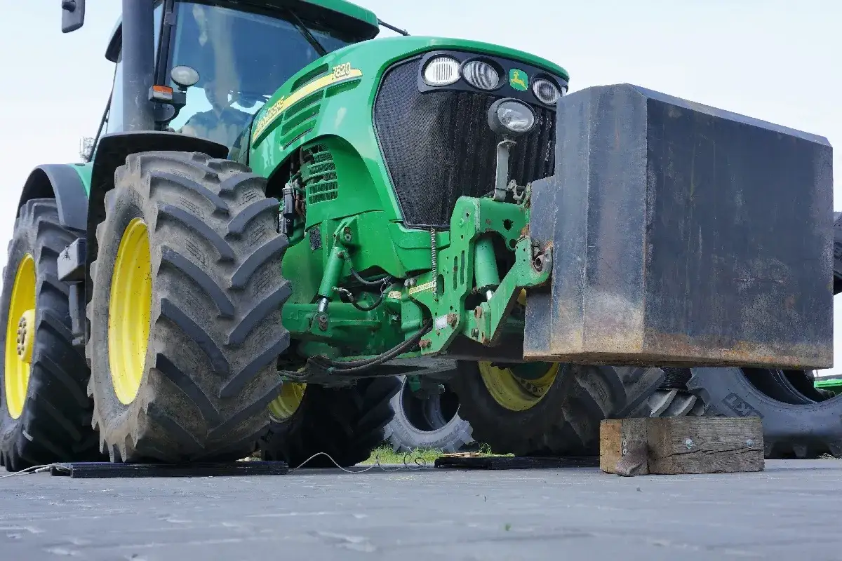 Zielony traktor John Deere z zamontowanym obciążeniem z przodu, gotowy do tractor pulling.