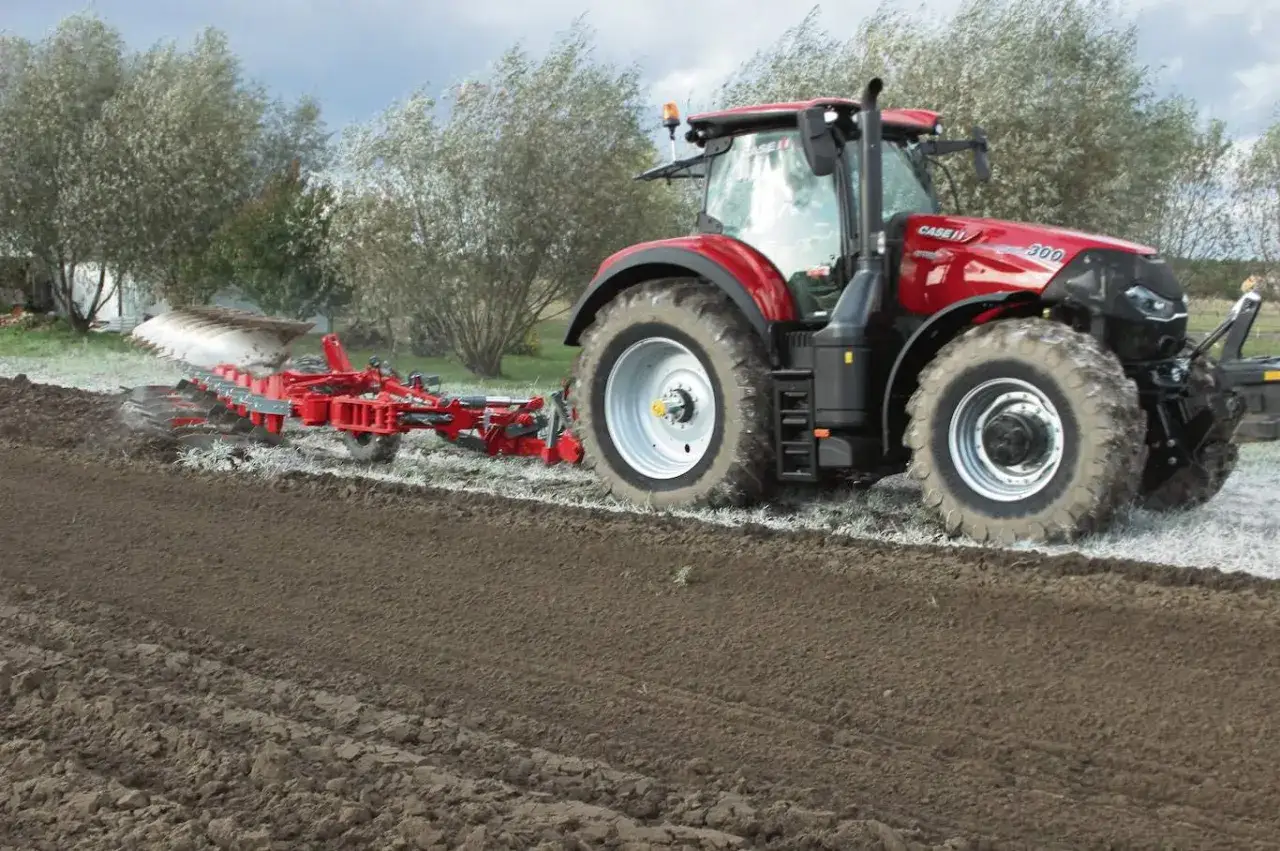 Czerwony traktor Case IH wykonuje oranie ziemi, przygotowując pole pod zasiew.
