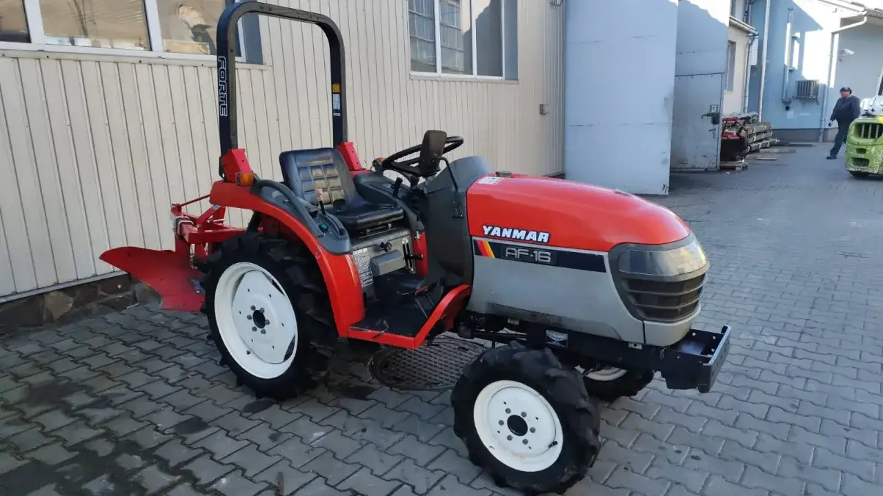Czerwony ciągnik Yanmar AF-16 z pługiem. To jest rewers w ciągniku, kt&oacute;ry pozwala na jazdę do tyłu.