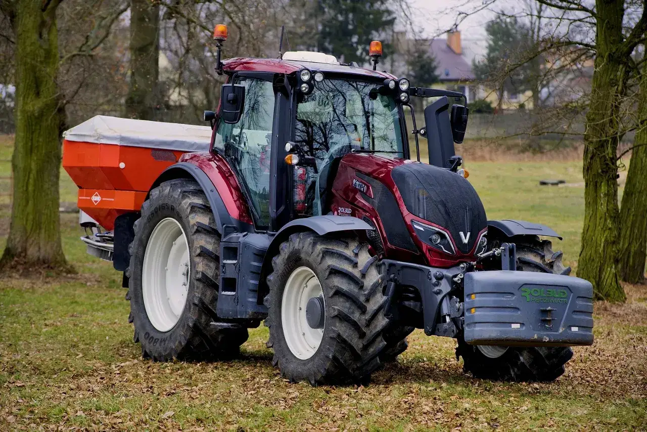 Czerwony ciągnik 4x4 z rozsiewaczem, idealny do prac polowych, w cenie do 30 tys.