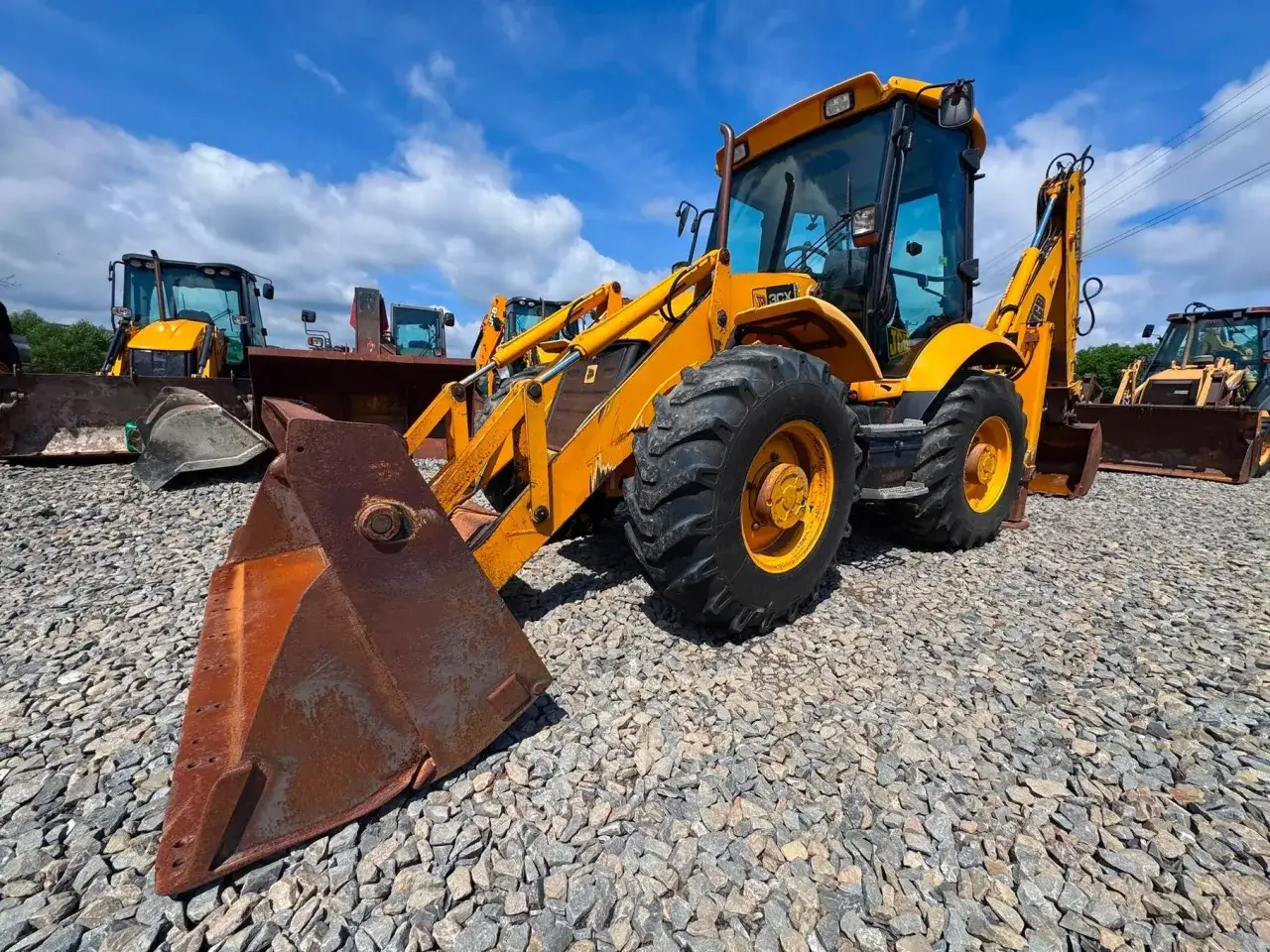 Ż&oacute;łta koparko-ładowarka JCB 4CX na placu budowy. Zastanawiasz się nad jej spalaniem?
