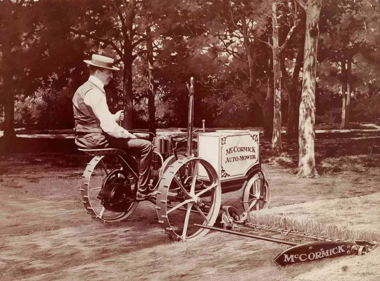Mężczyzna w kapeluszu siedzi na pierwszym traktorze na świecie, McCormick Auto-Mower, z kosą z przodu.