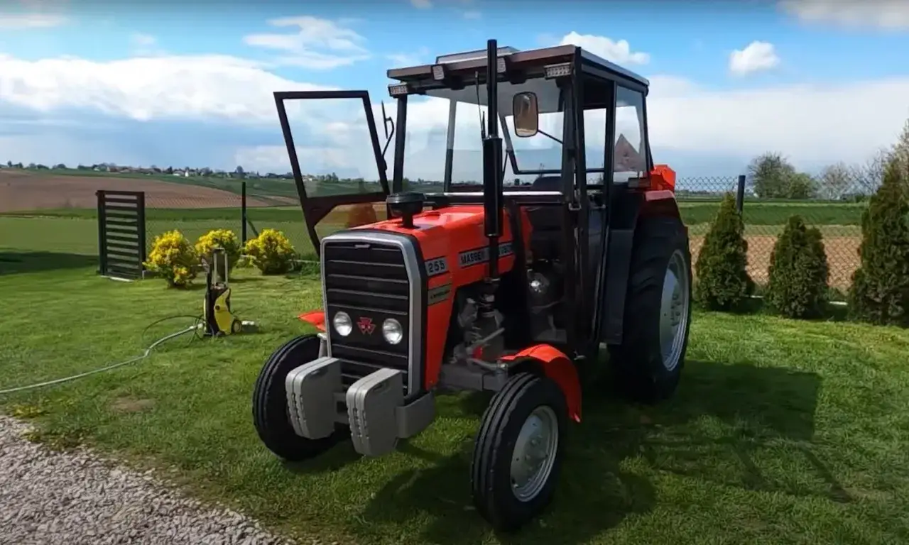 Czerwony traktor Massey Ferguson MF 255 z kabiną, gotowy do pracy. Jego waga pozwala na stabilność w polu.