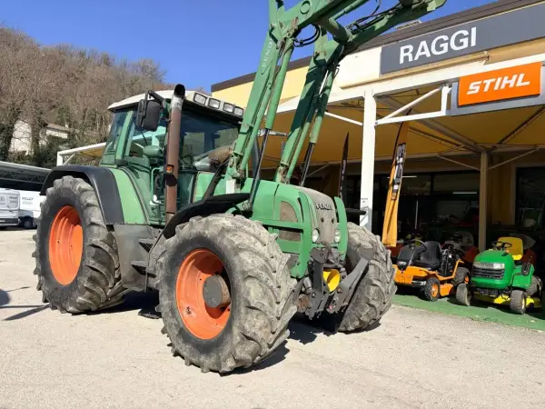 Zielony traktor Fendt 716 z ładowaczem, obok sklepu Raggi. Dane techniczne tego modelu są imponujące.