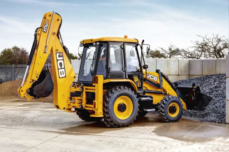 Żółty koparko-ładowarka JCB 3CX, gotowy do pracy. Jego waga pozwala na stabilność podczas kopania.